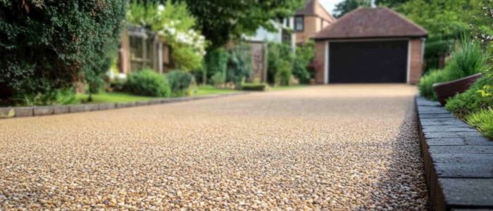 A chipseal driveway bordered by lush green bushes, showcasing a well-maintained outdoor space.