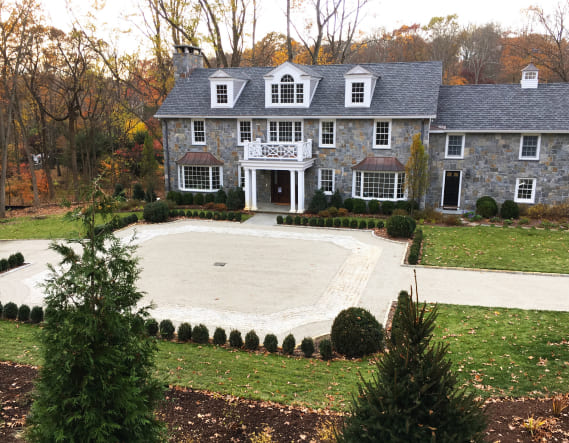 A large stone house with a chipseal driveway in Old Saybrook, CT, showcasing various chip sealing options.