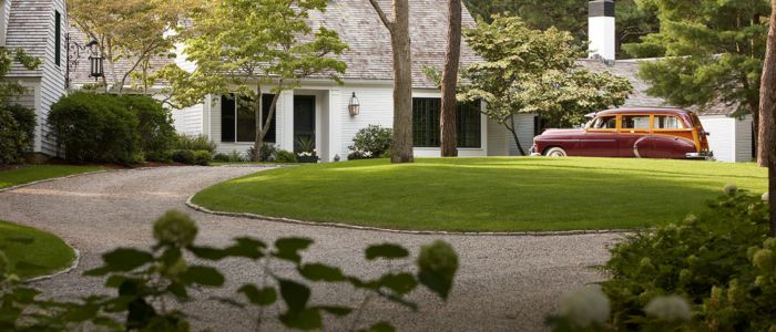 A car parked in the driveway of a house with a chip seal surface