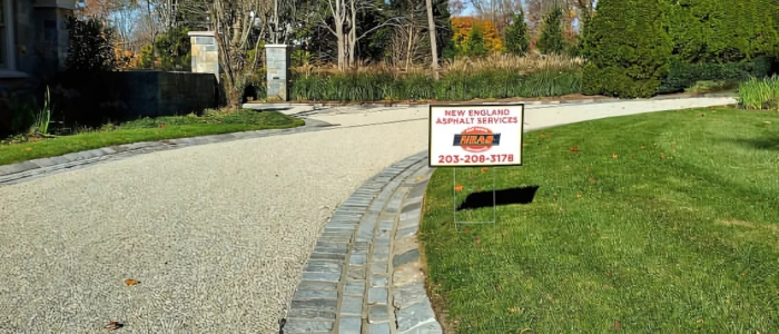 A gravel driveway with a sign, representing the concept of chip seal paving and its advanced applications.