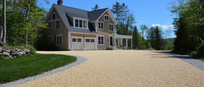 A gravel driveway in front of a house, highlighting the chip seal paving process, including drying and curing time.