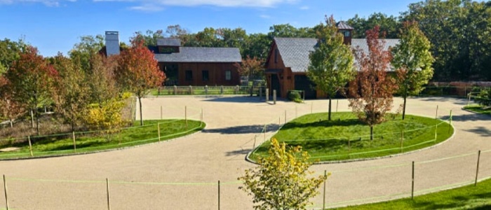 A circular driveway surrounded by trees and a fence, highlighting eco-friendly and sustainable chip and seal benefits.