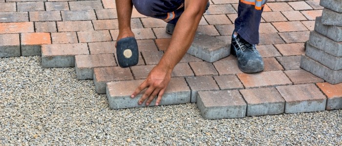 A man laying bricks to create an eco-friendly driveway path, focusing on the installation process.