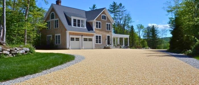 A gravel driveway leading to a house, showcasing an eco-friendly design with natural materials.