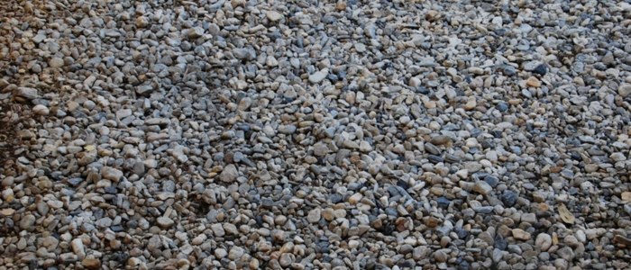 Close-up view of gravel on the ground, highlighting its texture and composition for comparison with chip seal.
