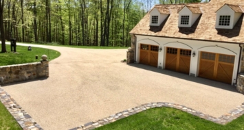 A driveway with a garage and a stone wall, emphasizing the all-weather capabilities of the Oil and Stone Driveway CT.