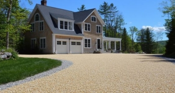A driveway in front of a house, emphasizing the enduring elegance of an oil and stone design.