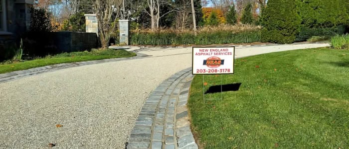 A gravel driveway with a sign, representing the concept of chip seal paving and its advanced applications.