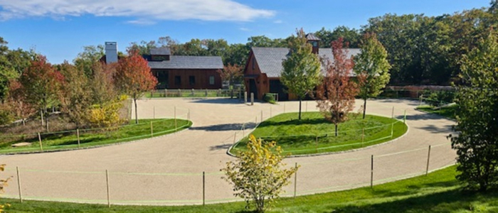 A circular driveway with lush trees and grass, highlighting the Oil and Stone Driveway Rejuvenation project in Martha’s Vineyard.