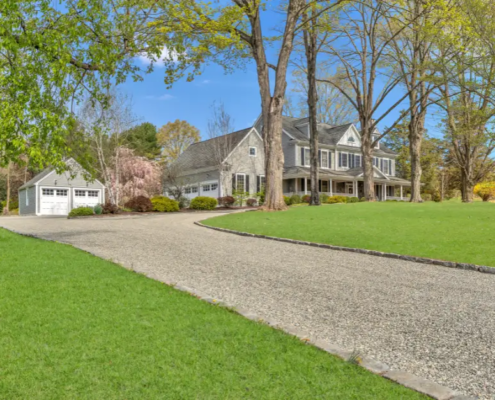 Chip seal driveway in Fairfield CT leading to a home with mature trees and detached garage.